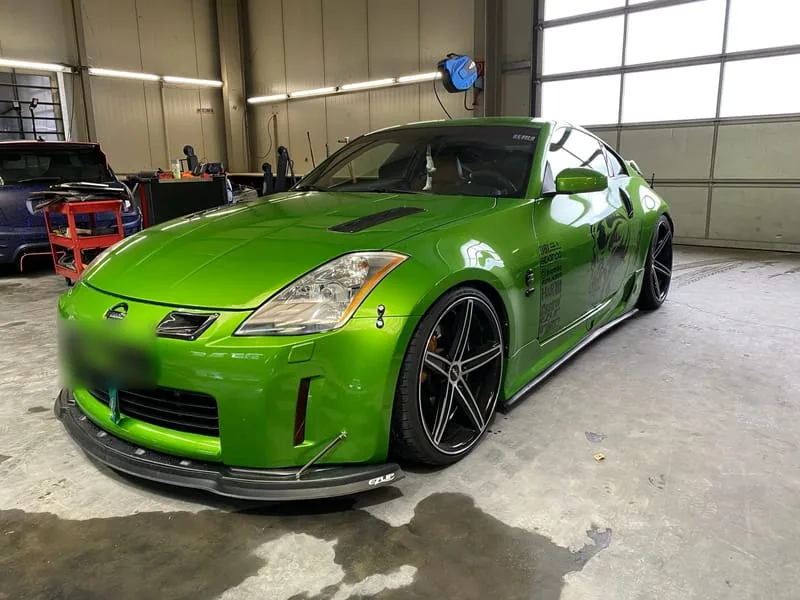 Grüner Nissan 350Z mit Breitbau-Karosserie und Frontsplitter in der Halle.