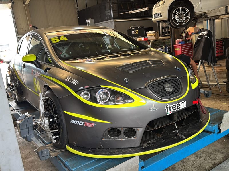 Gelb-anthrazitfarbener Seat-Cup-Rennwagen mit Startnummer 54 auf der Hebebühne.