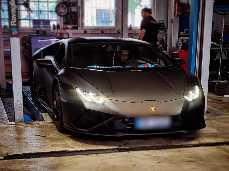 Mattgrauer Lamborghini Huracán mit eingeschalteten Scheinwerfern in der AZB-Halle.