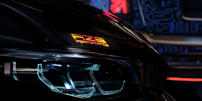 Nahaufnahme des LED-Scheinwerfers am BMW M850i mit orangem AZB-Performance-Schriftzug auf dem Kotflügel