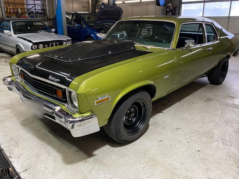 Olivgrüner Chevrolet Nova mit schwarzer Motorhaube in der AZB-Halle.