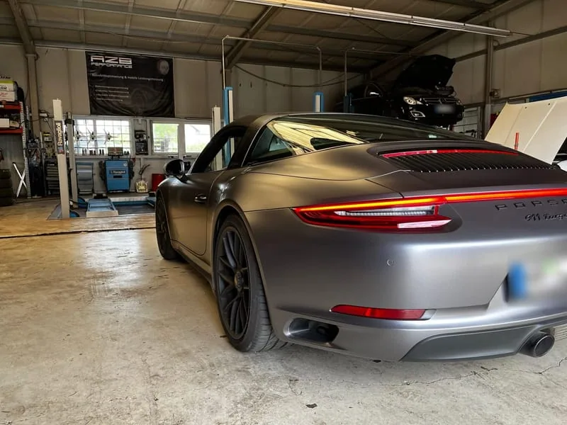 Heckansicht eines mattgrauen Porsche 911 in der Werkstatthalle.