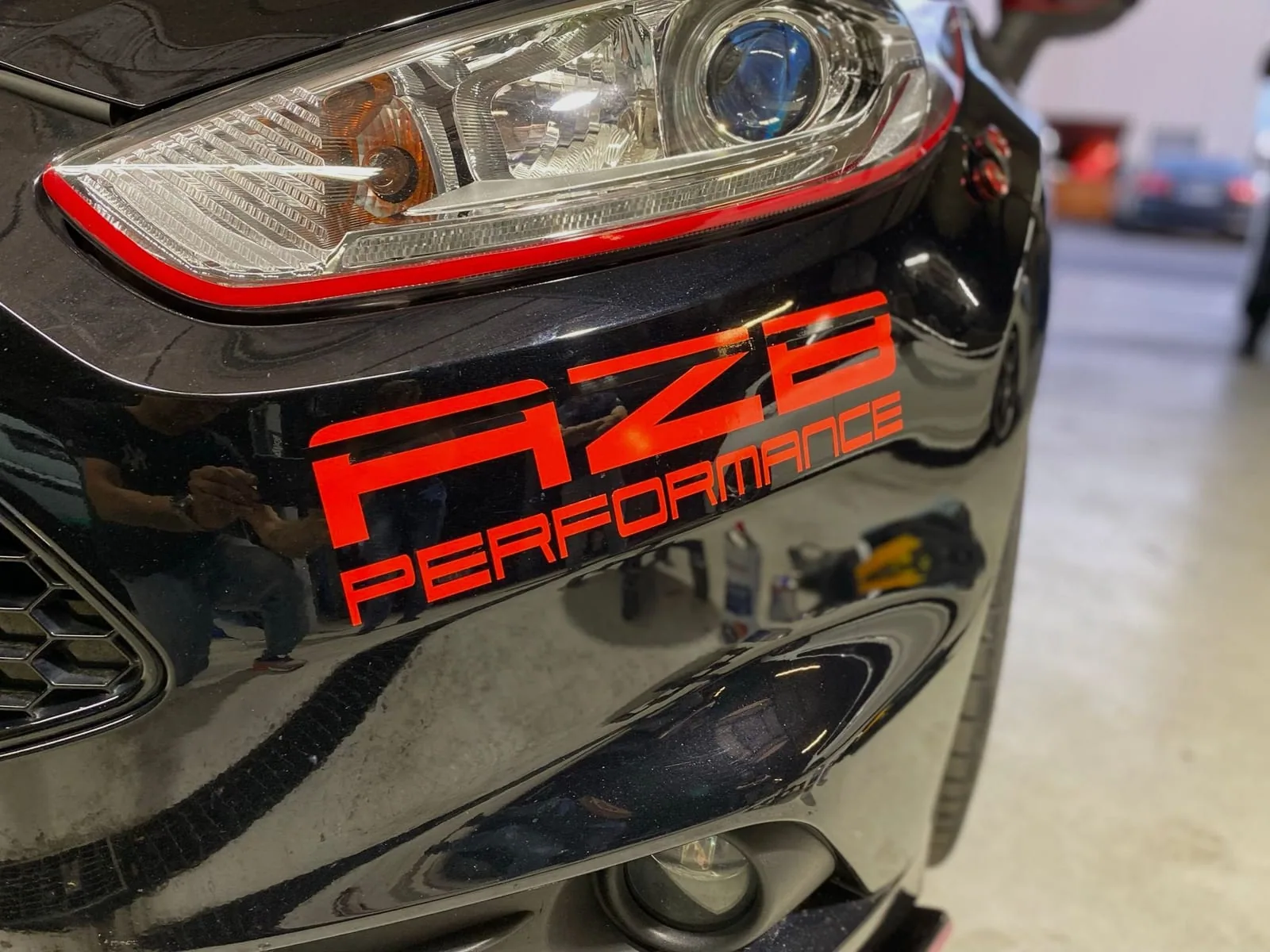 Roter AZB-Schriftzug auf dem schwarzen Lack eines Ford Fiesta ST