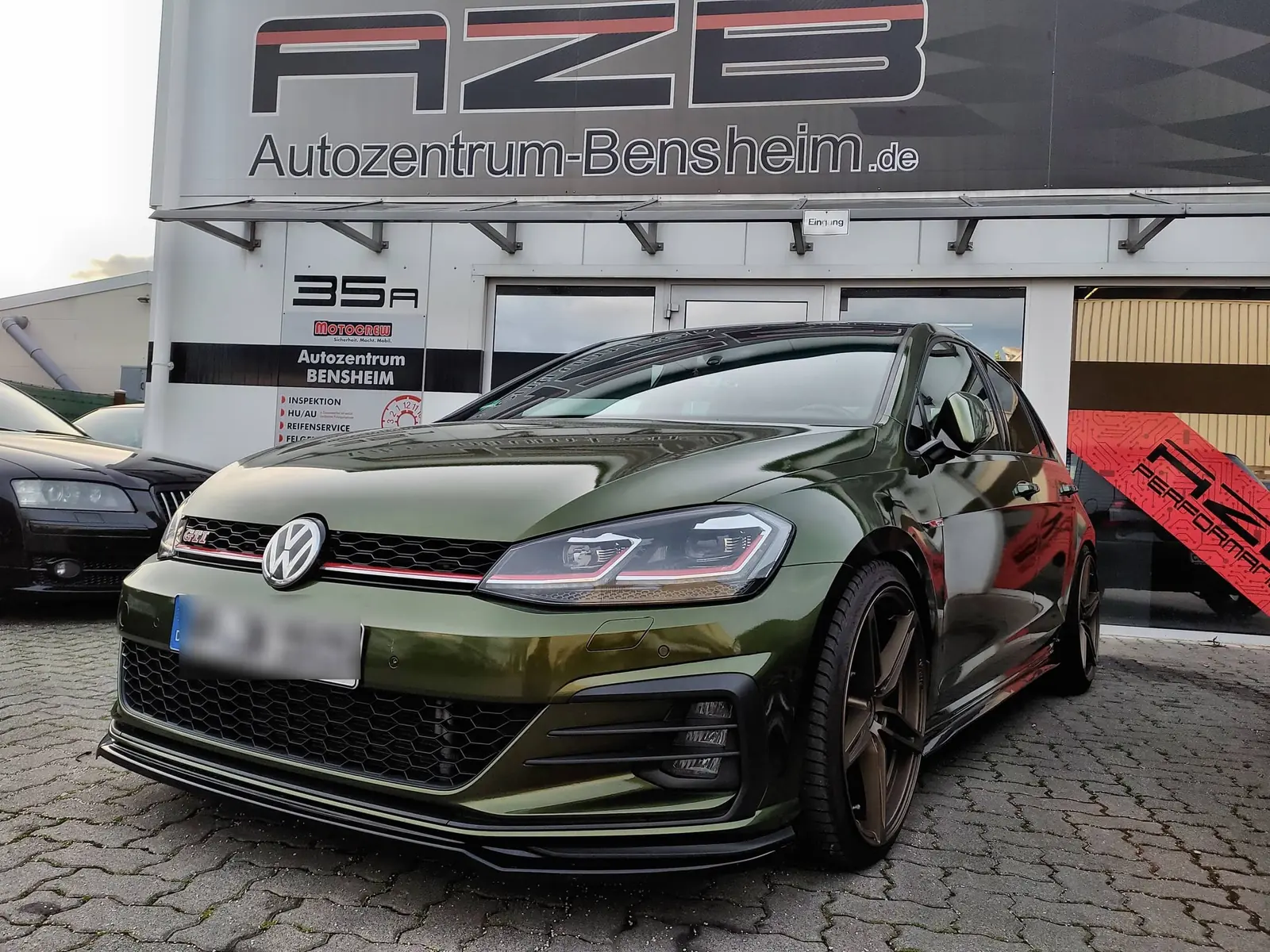 Folierter Golf GTI vor der AZB-Halle in Bensheim, Hallenschild und Leistungstafel im Hintergrund